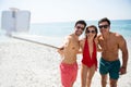 Happy young frends taking selfie through monopod at beach