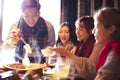 Happy young friends eating hot pot in restaurant at Royalty Free Stock Photo