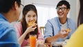 Happy young friends group having lunch at home. Asia family party eating pizza food and laughing enjoying meal while sitting at