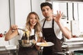 Happy young friends loving couple chefs on the kitchen cooking. Royalty Free Stock Photo