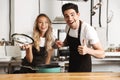 Happy young friends loving couple chefs on the kitchen cooking. Royalty Free Stock Photo