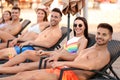 Happy young friends relaxing on deck chairs near pool Royalty Free Stock Photo