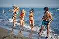 Happy friends with water guns have fun on the beach at sea