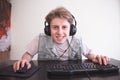 Young gamer with headphones plays computer games at home and smiles