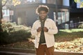 Happy young gen z African American guy standing at sunny street in city park. Royalty Free Stock Photo