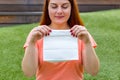 Happy young ginger woman looking a white paper bag in her hands. Female holding packet with food. Copy space. Mockup of Royalty Free Stock Photo