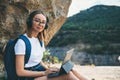 Happy young girl with glasses and backpack enjoying summer holidays listen music in headphones and laptop in nature, woman Royalty Free Stock Photo