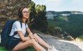 Happy young girl with glasses and backpack enjoying summer holidays listen music in headphones in nature, fun traveler woman rest Royalty Free Stock Photo