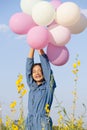 Happy young girl hold balloon at yeloow flower park with blue sky