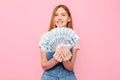 Happy young girl holding cash dollar bills on an isolated pink background Royalty Free Stock Photo