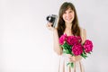 Happy young girl holding in hands bouquet of peony and old vintage camera. Smiling woman, sweet romantic moment. Royalty Free Stock Photo