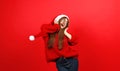 Happy young girl listens to Christmas music in headphones and dances on a red background Royalty Free Stock Photo