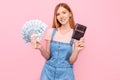 Happy young girl with money fan and passport isolated on pink background