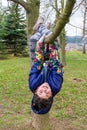 Happy young girl playing hanged on tree outside