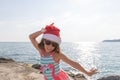 Happy young girl with red Santa hat and long hear jumping, dancing, has fun on topical beach, holiday Christmas, new Royalty Free Stock Photo