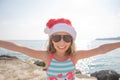 Happy young girl with red Santa hat and long hear jumping, dancing, has fun on topical beach, holiday Christmas, new Royalty Free Stock Photo