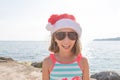 Happy young girl with red Santa hat and long hear jumping, dancing, has fun on topical beach, holiday Christmas, new Royalty Free Stock Photo
