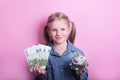 Happy young girl with silver piggy bank and euro banknotes  on pink background. save money concept. Royalty Free Stock Photo