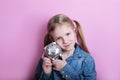 Happy young girl with silver piggy bank on pink background. save money concept. Royalty Free Stock Photo