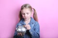 Happy young girl with silver piggy bank on pink background. save money concept.