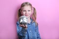 Happy young girl with silver piggy bank  on pink background. save money concept. Royalty Free Stock Photo