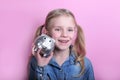 Happy young girl with silver piggy bank  on pink background. save money concept. Royalty Free Stock Photo