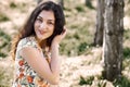 Happy young girl sitting on a log in the forest, bright sunlight around, beauty of nature in spring Royalty Free Stock Photo