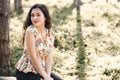 Happy young girl sitting on a log in the forest, bright sunlight around, beauty of nature in spring Royalty Free Stock Photo