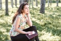 Happy young girl sitting on a log in the forest, bright sunlight around, beauty of nature in spring Royalty Free Stock Photo