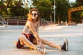 Happy young girl sitting on a skateboard Royalty Free Stock Photo