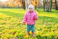 Happy young girl smiling in beautiful autumn park on nature walks outdoors. Little child playing with falling yellow maple leaf in Royalty Free Stock Photo