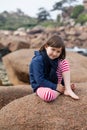 Happy young girl smiling, relaxing on a giant granite stone