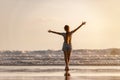 Happy girl is standing with open arms at sunset sea beach Royalty Free Stock Photo