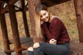 Happy young girl in a stylish sweater sits in a wooden pergola