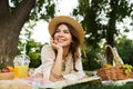 Happy young girl in summer hat having a picnic at the park, Royalty Free Stock Photo