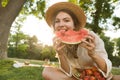 Happy young girl in summer hat having a picnic at the park, sitting on a grass Royalty Free Stock Photo