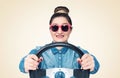 Happy young girl in sunglasses drives a car while holding a steering wheel, front view, auto concept Royalty Free Stock Photo