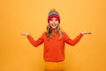 Happy Young girl in sweater and hat shrugs her shoulders