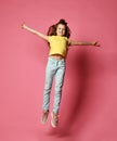 Happy young girl or teen girl in jeans and yellow t-shirt jumps high like she is flying high in skies with her arms spread