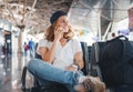 Happy young girl traveler with a phone in hand at the airport in the departure area. She speaks on a mobile phone Royalty Free Stock Photo