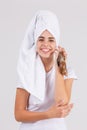 A happy girl, with a towel wrapped on a head, holds a Ahatina snail and laughs. The concept of beauty. Royalty Free Stock Photo