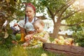 The happy young girland baby during picking apples in a garden outdoors