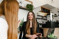 Happy young girlfriends in formal clothes are sitting at a table in a cozy cafe for a break and chatting with a smile on their Royalty Free Stock Photo