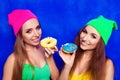 Happy young girls in hats holding sweet donutes Royalty Free Stock Photo