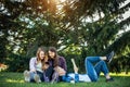 Happy young girls have fun laughing sitting on green grass in the park. Students in between lectures. Blonde, brunette Royalty Free Stock Photo