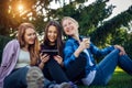 Happy young girls have fun laughing sitting on green grass in the park. Students in between lectures. Blonde, brunette and red Royalty Free Stock Photo