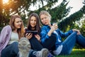 Happy young girls have fun laughing sitting on green grass in the park. Students in between lectures. Blonde, brunette and red Royalty Free Stock Photo