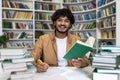 Smiling student studying with books at library in preparation for university exams Royalty Free Stock Photo