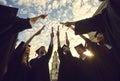 Happy young graduates in black mantle proudly raising their scrolls of diplomas up against the sky. Royalty Free Stock Photo