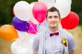 Happy young groom holding in hands colorful latex balloons